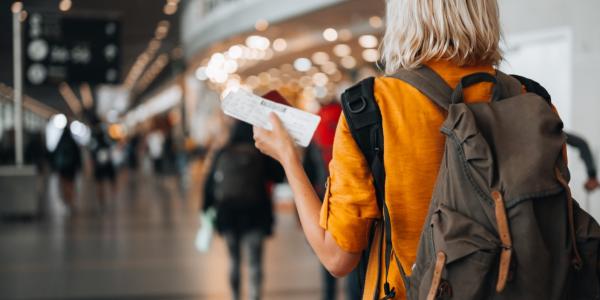 Person at the airport holding a boarding pass as they walks to their departure gate.