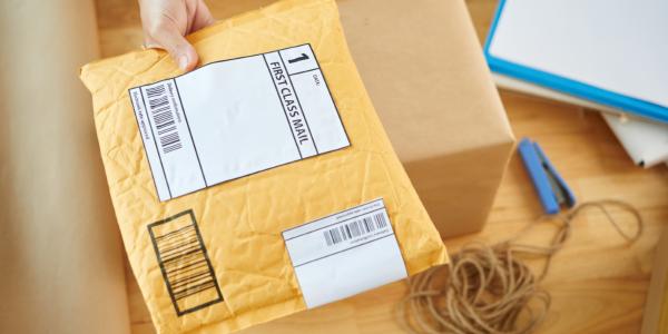 Young person holding first class mail in envelope.