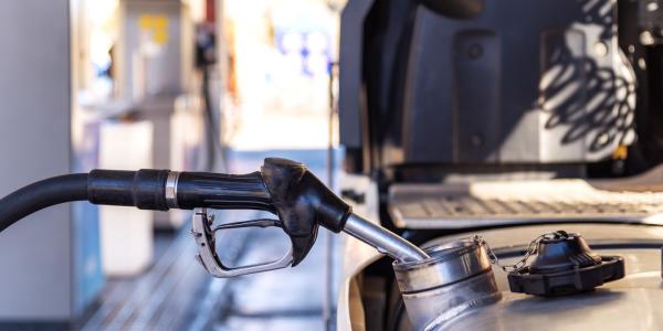 Close-up of the gas pump nozzle inserted in a commercial truck's gas tank.