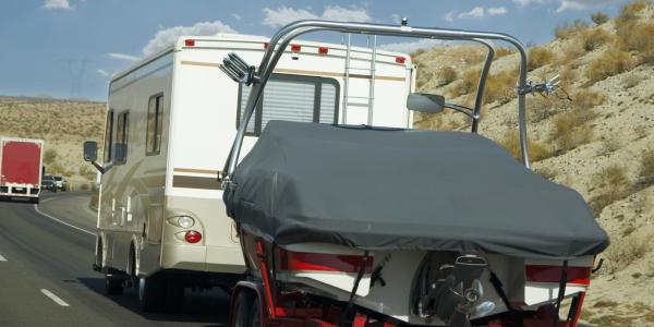 An R.V. towing a boat on a road trip.