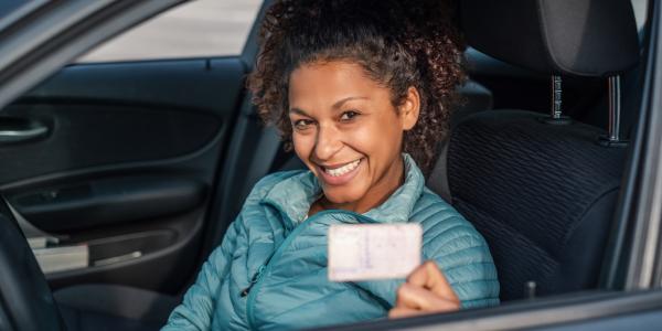 Person smiling showing driving license.